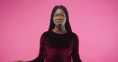 Afro-Amerikalı güzel bir kadının yakın plan portresi olumsuz tepki veriyor. Kafasını sallayarak ciddi bir yüz ifadesine karşı çıkan bir şeyin pembe duvarın üzerinde izole bir şekilde durması bir fikir gibi değil.