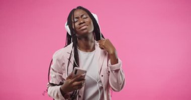 Neşeli Afro-Amerikan güzel bayan portresini yakından çek. En sevdiği şarkıları dinleyen ve kulaklıkla müzik eşliğinde hareket eden akıllı telefon. Boş zaman konsepti