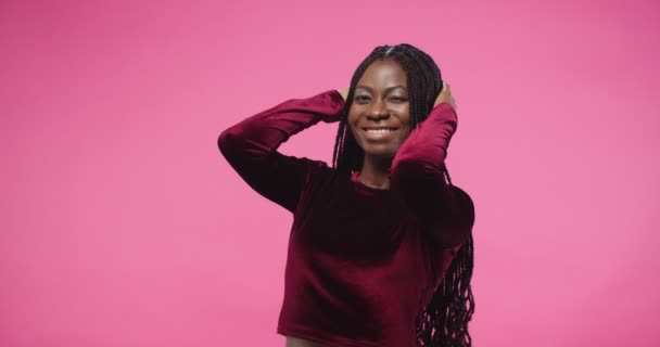 Close up retrato de feliz alegre jovem mulher afro-americana bonita de pé sobre fundo rosa em estúdio posando em diferentes poses engraçadas com sorriso no rosto olhando para a câmera. conceito de modelagem — Vídeo de Stock