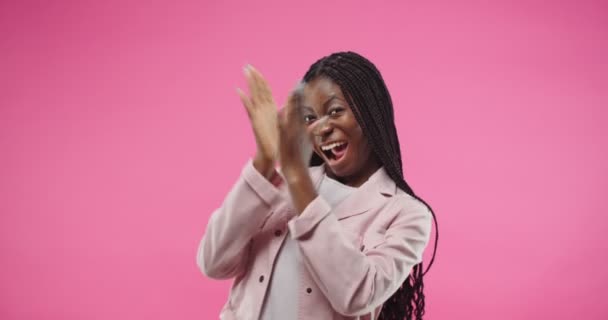 欢快快乐的非洲裔美国人的画像，漂亮的年轻女性带着音乐节奏地微笑和跳舞，拍拍着她的手，在玫瑰红的背景下做出滑稽的动作。有趣的概念 — 图库视频影像