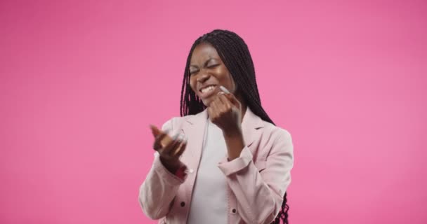 Retrato de feliz jovem afro-americano bela mulher sorrindo e dançando a música fazendo movimentos rítmicos movendo as mãos em pé sobre fundo rosa em estúdio. a celebrar a diversão. Conceito de dançarina — Vídeo de Stock