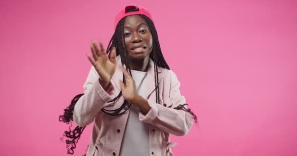 Portrait of African American young beautiful cheerful woman wearing red cap in positive mood funny moving and dancing making gestures with hands celebrating win, expressing joy, isolated on rosy wall — Stockvideo