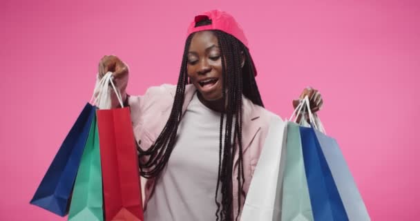 Portrait of cheerful young beautiful African American woman teen holding many colorful shopping bags in hands with purchases with satisfied face after buying stuff. Positive emotions, buyer concept — 图库视频影像