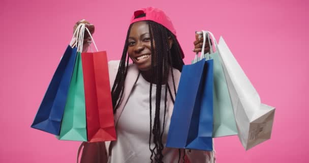 Portrait of happy young African American woman holding many shopping bags in hands showing purchases to camera smiling with satisfied face expression. Buying stuff, shopaholic concept — Vídeo de stock