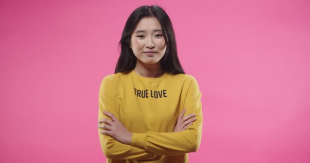 Portrait of happy pretty positive Asian young woman in yellow blouse standing on pink wall background, looking at camera and smiling posing in studio. Modeling concept, teen beautiful female — 비디오