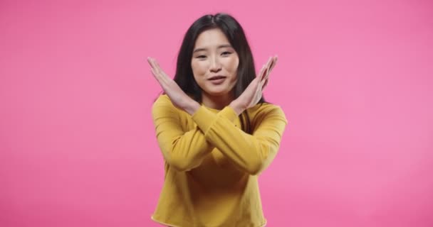 Portrait of pretty happy Asian young woman saying NO denying something, disagreeing, rejecting while standing isolated on pink background in studio. Negative reaction, expressing disagreement – Stock-video