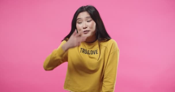 Portrait of beautiful Asian young woman saying NO denying something, rejecting and covering face with hand dont want to watch while standing isolated on pink background in studio. Negative reaction — Vídeo de Stock