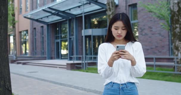 Slow motion Cheerful asian woman looking at mobile phone walking in the street to the office business urban people commuter with cellphone in hand — 图库视频影像