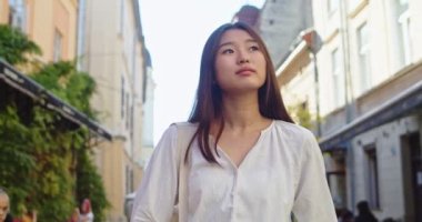 Eski Avrupa şehrinin sokaklarında yürüyen ve binalara bakan çekici genç bir bayan. Asyalı bir kadın yaz tatilinde seyahat ediyor ve iyi vakit geçiriyor. Dinlenme, tatil konsepti.