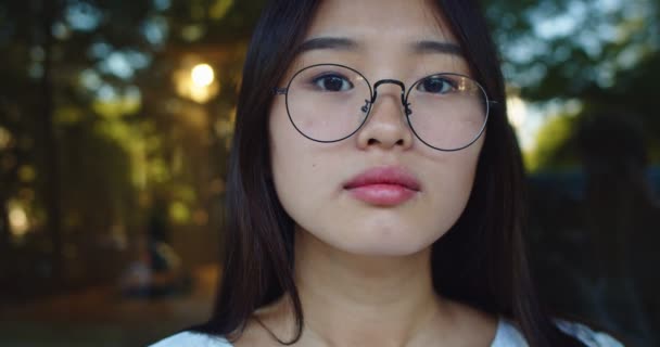 Gros plan de charmante jeune femme face à la caméra dans la rue du parc les jours d'été. Femme asiatique remettant des lunettes et souriant. Concept humain. Urbain, arrière-plan urbain. — Video