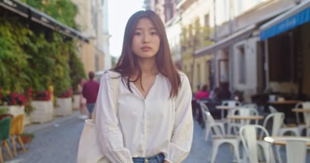 Portrét půvabné asijské ženy s eko taškou stojící uprostřed ulice centra města. Mladá studentka v neformálním oblečení, dívá se venku na kameru. Koncept chůze, volného času. — Stock video