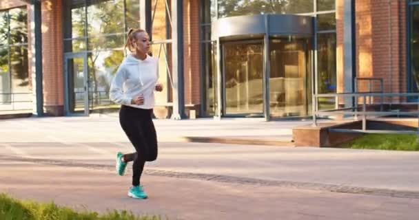 Yarışmadan önce sıkı çalışan uluslararası kadın koşu antrenmanı şampiyonunun yan görüntüsü. Yetişkin, beyaz bir kadın şehir sokağında ısınıyor. Spor, sağlık konsepti. — Stok video