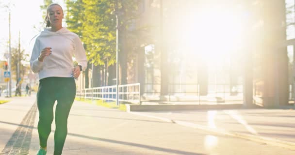 Femme caucasienne précipitée dans l'entraînement de vêtements de sport, s'entraînant le matin. Jolie jeune athlète féminine est à court d'haleine après le jogging, séance de course dans la rue de la ville urbaine. Sport, santé, fitness. — Video