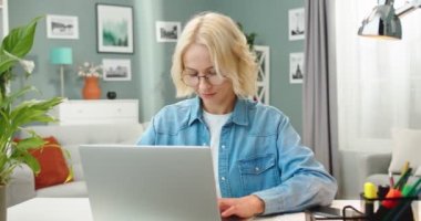 Güzel, genç, beyaz bir kadın laptopta ders çalıştıktan sonra gözlüğünü çıkarıyor. Evde çalışan bilgisayar kullandıktan sonra göz yorgunluğu çeken aşırı çalışan bir kadın.
