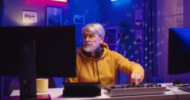 Kafkasyalı yaşlı DJ 'in portresi stüdyo atölyesinde müzik çalıyor. Son sınıf öğrencisi odada ekipmanla müzik yapıyor. Yaratıcı atmosfer müziği. Ses çıkarıcı. Renkli Neon ışığı