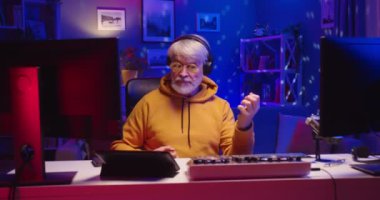 Yaşlı beyaz adam DJ 'lik yapıyor. Profesyonel mikser ekipmanları üzerinde çalışıyor. Coronavirus covid 19 tecridi sırasında müzisyen canlı yayında.