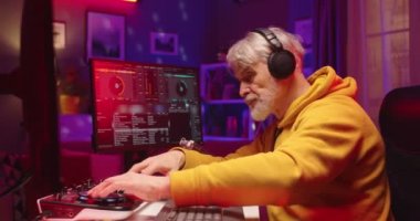 Akşamları canlı yayında plakalarla karışık müzik yapan beyaz bir adamın yan görüntüsü. Son sınıf DJ 'i, geceleri evdeki stüdyoda bilgisayardaki konsol karıştırıcısında ses ritmi yaratıyor.