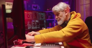 Akşamları stüdyoda canlı müzik eşliğinde plakalarla karışık mutlu beyaz adam görüntüsü. Erkek DJ bilgisayardaki konsol karıştırıcısında ses yaratıyor. Kapat