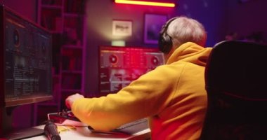 Evde müzik kayıt stüdyosunda çalışan Kafkasyalı yaşlı ses mühendisi, modern şarkı yaratıcı DJ sanatçısı, masa kontrolü yüzeyi üzerinde çalışan bir sanatçı yaratmak için karışık tahta ve yazılım kullanıyor.