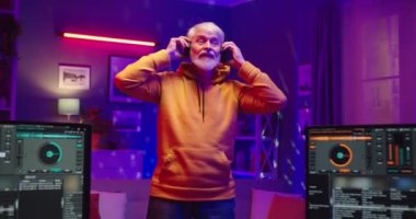 Evde kayıt stüdyosunda gitar çalıyormuş gibi yapan mutlu, komik, yaşlı, beyaz, erkek müzisyen portresi. Erkek DJ ve karıştırma tahtası ve bilgisayar monitörleri