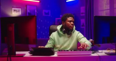 Yakışıklı DJ ev kayıt stüdyosunda müzik çalıyor. Öğrenci yaratıcı atmosfer müziği yazmayı öğreniyor. Ses çıkarıcı. Renkli neon ışıklı genç Afrikalı Amerikalı erkek karıştırıcı konsolu üzerinde çalışıyor