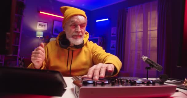 Portrait d'homme retraité caucasien élégant DJ jouant de la musique au studio d'enregistrement à la maison mélangeant sur plaque de vinyle. Vieil homme mélangeant les sons sur console mélangeur équipement assis à la table dans l'appartement — Video