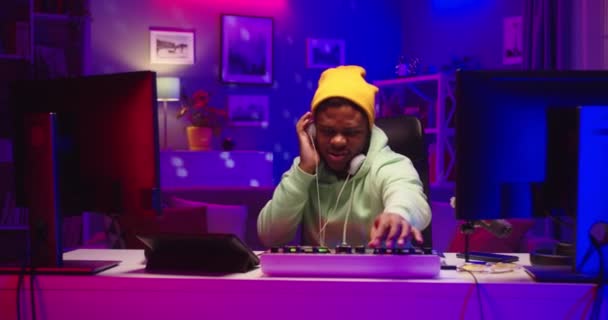 Afro-Amerikaanse professionele dj speelt coole clubmuziek op draaitafel console in de thuisopnamestudio. portret van knappe creatieve man krabben vinyl draaien hendels op mixer creëren hit — Stockvideo