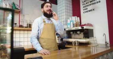 Çekici beyaz adam telefonda müşteriyle konuşuyor ve ön sipariş alıyor. Kahvehanedeki içecek menüsü için danışmanlık yapan genç bir barista. İş, iletişim konsepti.