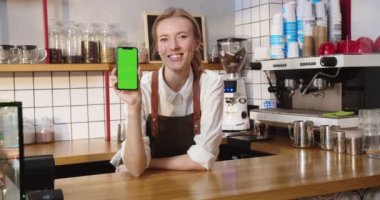 Güzel bayan kafe sahibinin portresi bara yaslanmış ve yeşil ekranı gösteriyor. Kafkasyalı yetişkin bir kadın kameraya bakıyor ve kahve dükkanında krom anahtar kırıyor. Kariyer konsepti.