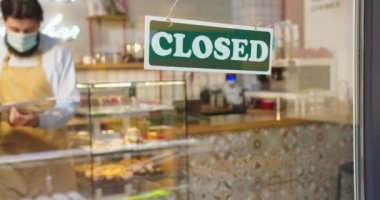 Açık havada tıbbi maskeli yetişkin bir erkek barmen kafenin penceresine gelip affedersiniz, kapalıydı. Kafkasyalı küçük işletme sahibi covid-19 yüzünden kafeyi kapatıyor. Kilitlenme.