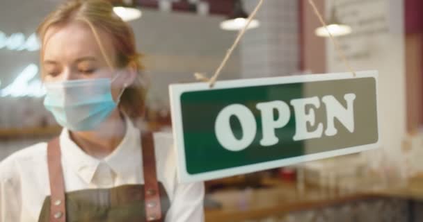 Hüsrana uğramış kadın kafe sahibi Coronavirus kilitlenmesi sırasında kriz nedeniyle kafeyi kapatıyor. Meicla maskeli yetişkin bir kadın pencereye kapalı bir duyuru yaptı. İş konsepti — Stok video
