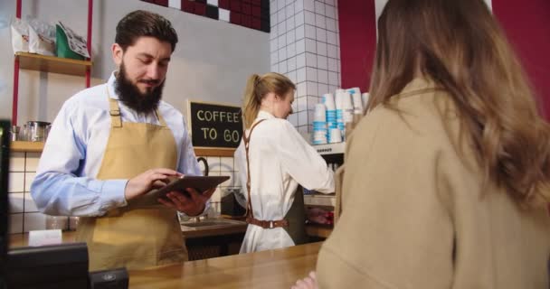 Kompetent personal på kaféet som serverar unga kvinnliga kunder. Vuxen man kassör ta ordning och sätta den på tablett professionell bartender gör dryck och ge till kvinnan. Näringsliv. — Stockvideo