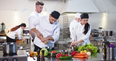 Kafeterya mutfağında iş akışı. Meşgul karışık ırk aşçıları ünlü restoranda yemek hazırlıyor. Kafkasyalı genç adam, Asyalı bayan meslektaşımla restoranda yemek hazırlıyor. Aşçılık konsepti.