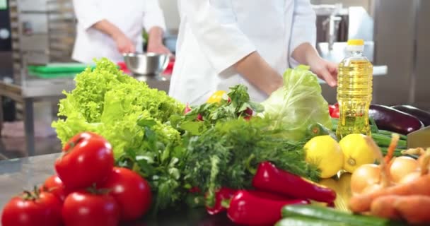 Close-up van vrouwelijke handen nemen van groenten van tafel. Verse groenten, groene salade, rode peper, tomaat, salade bereiding, restaurant keuken. Chef-kok bereidt levensmiddelen, werkconcept — Stockvideo