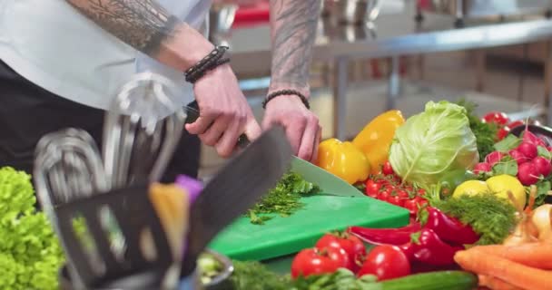 Mãos de homem com tatuagens cortando e fatiando salsa verde trabalhando no restaurante. Chef de homem profissional preparando prato vegetal com verdes, salada, picando ingredientes na cozinha. Conceito de close up — Vídeo de Stock