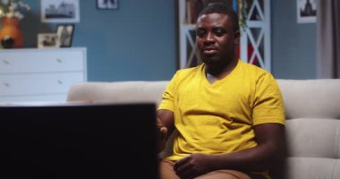 Akşamları evde sıkı çalıştıktan sonra kanepede takılan yakışıklı bekar adam. TV izleyen ve kanal değiştiren genç bir Afro-Amerikalı. Eğlence, teknoloji konsepti.