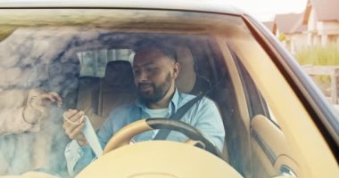 Yakışıklı genç bir adamın mutlu bir şekilde araba sürüşüne yakından bakın. Gökyüzü araba camlarına yansıyor. Sakallı ve şizofren, tıbbi maske takan mutlu bir şoför. Yaşam tarzı, yol, araba, sürücü kavramı.