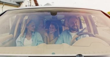 Mutlu ve sevgi dolu ebeveynler ve heyecanlı çocukları şehirde gülen araba kullanırken konuşuyorlar. Genç bir aile yazın arabayla yurt dışına seyahat ediyor. Yaşam tarzı kavramı, mutlu aile, birlikte seyahat..