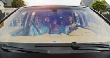 Sevgi dolu ebeveynler ve çocukların şehirde araba sürerken gülümsemesi ve kahve içmesi ön planda. Genç bir aile yazın arabayla yurt dışına seyahat ediyor. Yaşam tarzı kavramı, mutlu aile, birlikte seyahat..