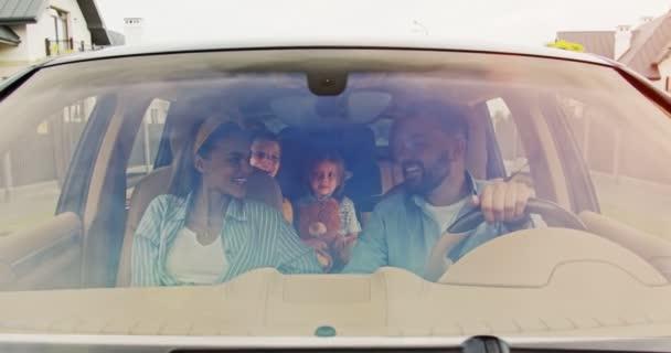 Front view of happy loving parents and excited kids speaking and smiling driving car in city. Young family having vacation together in summer. Concept of lifestyle, happy family, travel together. — Stock Video