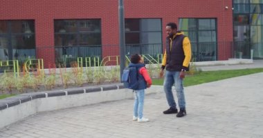 Mutlu Afrikalı yakışıklı Amerikalı baba ve oğul okulun yanında durmuş keyifli sohbet ediyorlar. Neşeli okul çocuğu babasıyla konuşuyor ve ona bir şey gösteriyor. Okula geri dön.