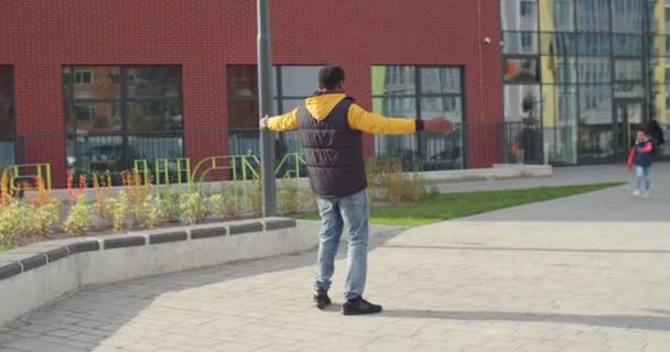 Vrolijke Afro-Amerikaanse jonge liefhebbende vader ontmoet zijn zoontje van school na lessen buiten op straat. Gelukkige junior leerling in goed humeur loopt naar vader na de lessen. Onderwijsconcept — Stockvideo