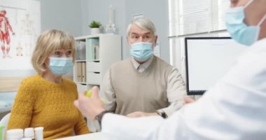 Klinikte doktorla sohbet ederken tıbbi danışmanlık yapan Kafkas aile çiftinin portresi. Doktorlar hastalara ilaç ve tedavi veriyor. Hemşire arka plan konsepti üzerinde çalışıyor.