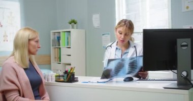 Sarışın bir kadının kadın doktorla röntgen çektirdiği orta boy bir fotoğraf. Hastane kliniğinde sağlık hizmeti sunan tıp doktoru. Sağlık, sağlık, tıp konsepti