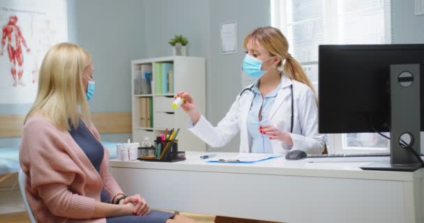 La inyección media del médico femenino en la máscara médica que da vitaminas medicinales a la mujer hermosa rubia en la visita médica en el hospital. Mujer joven en el consultorio médico. Concepto de salud, salud y medicina — Vídeo de stock