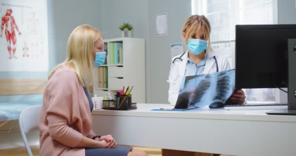 Colpo medio di donna in maschera medica guardando i raggi X con medico femminile. Specialista medico che fornisce servizi sanitari in clinica ospedaliera. Concetto di sanità, salute e medicina — Video Stock