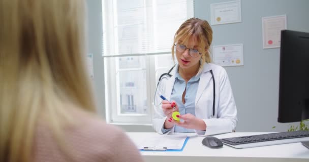 Detailní záběr ženského lékaře dávat léky vitamíny krásné ženě na lékařské návštěvě v nemocnici. Lékařský specialista poskytující zdravotní služby na klinice. Zdravotní péče, medicína koncept — Stock video