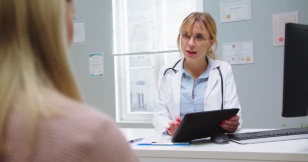 Close up de médico fêmea em óculos olhando para tablet. Mulher em visita médica no hospital. Médico especialista em prestação de serviços de saúde em consultório hospitalar. Saúde, conceito de medicina — Vídeo de Stock