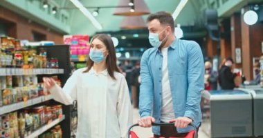 Happy multiethnic couple buying pillows in house improvement store. Low angle view of cheerful husband and wife with shopping cart purchasing decorations for home in furniture store