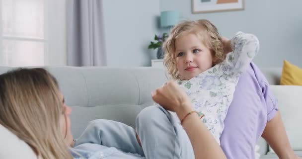 Middle plan of young mommy and cute daughter playing in living room, playful family mother with little child girl having fun clap hands together, tickling. Concept of family, parenthood, togetherness. — Stock Video